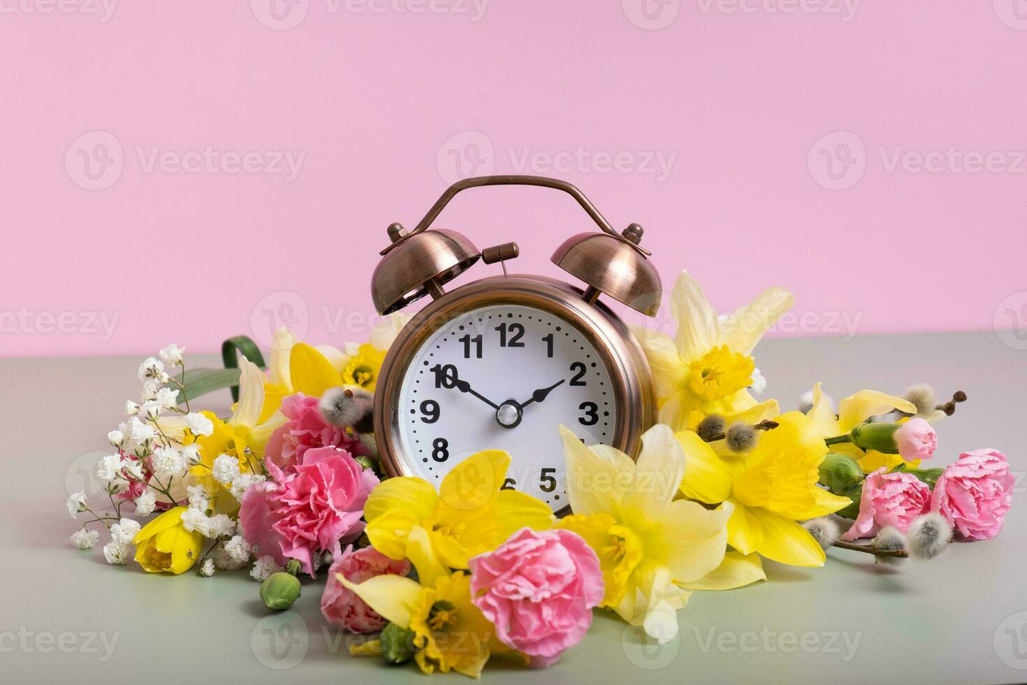 Alarm clock with spring flowers. Spring time, daylight savings concept, spring forward photo