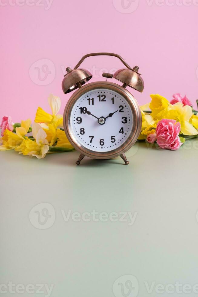 Alarm clock with spring flowers and copy space. Spring time, daylight savings concept, spring forward photo