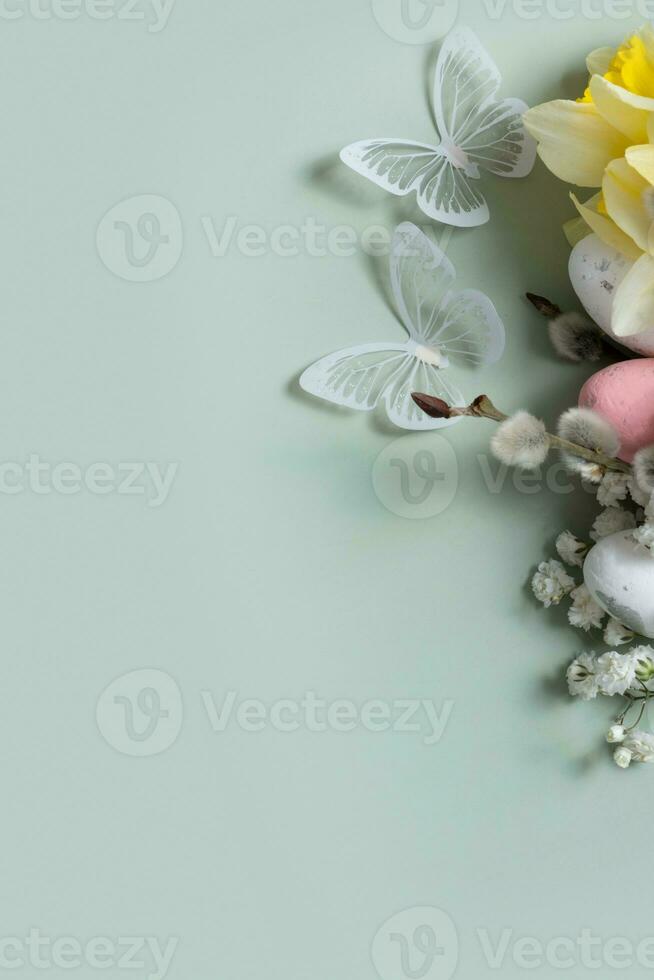 Butterflies and flowers, easter eggs and willow on green background with copy space. Easter greeting card template photo