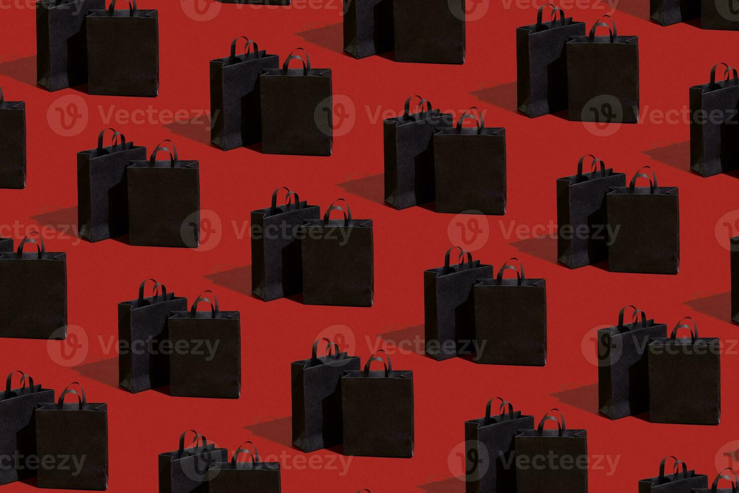 Black paper shopping bags pattern on red background. Black friday sale, shopping concept. photo