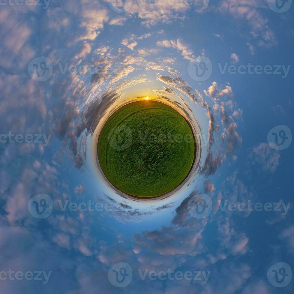 green tiny planet in evening blue sky with beautiful clouds. Transformation of spherical panorama 360 degrees. Spherical abstract aerial view. Curvature of space. photo