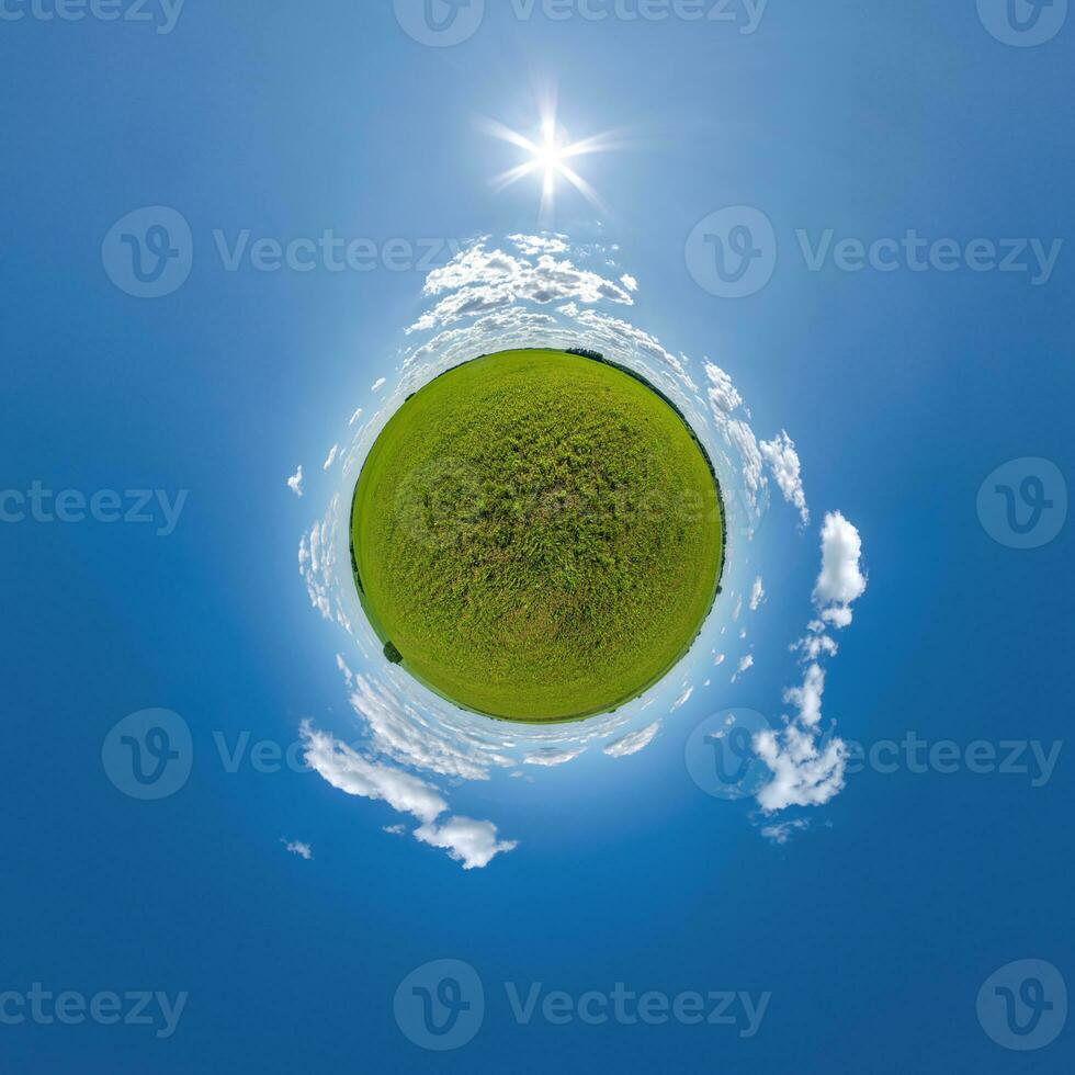green tiny planet in evening blue sky with beautiful clouds. Transformation of spherical panorama 360 degrees. Spherical abstract aerial view. Curvature of space. photo