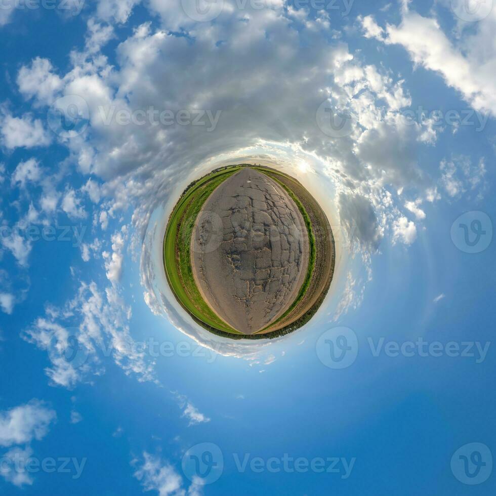 green tiny planet in evening blue sky with beautiful clouds. Transformation of spherical panorama 360 degrees. Spherical abstract aerial view. Curvature of space. photo