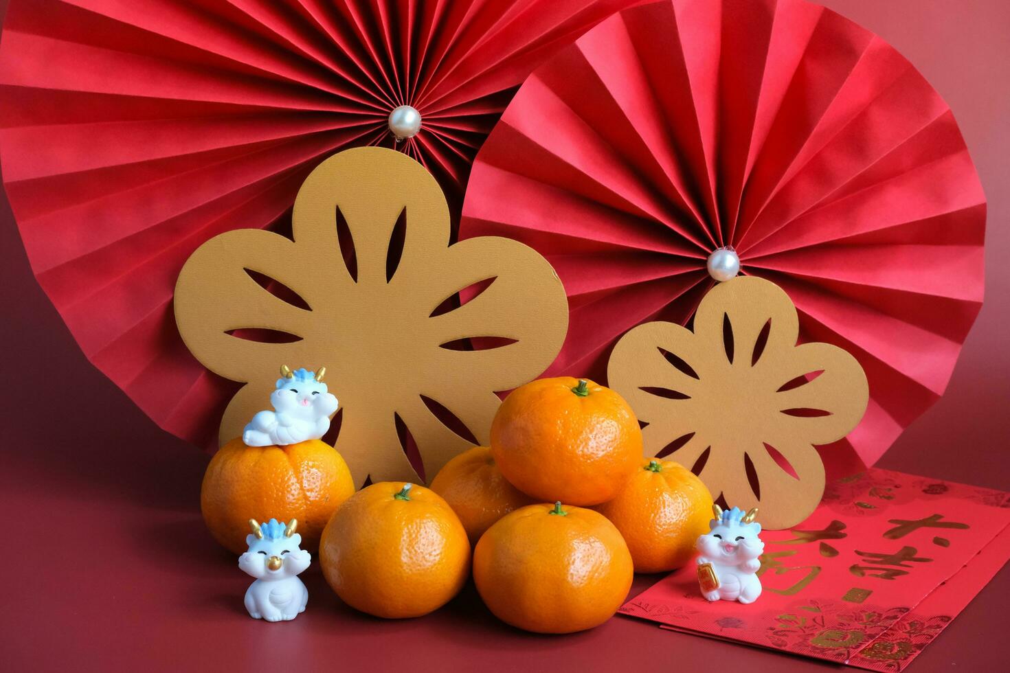 Chinese New Year of the dragon festival concept. Mandarin orange, red envelopes, dragon and gold ingot with red paper fans. Chinese character da ji da li meaning great luck great profit. photo