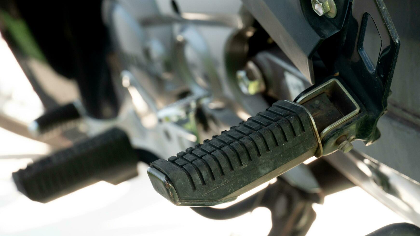 Close up of motorcycle footrest pedals. under view of motercycle stop with stand. Bright of sunlight for background. photo