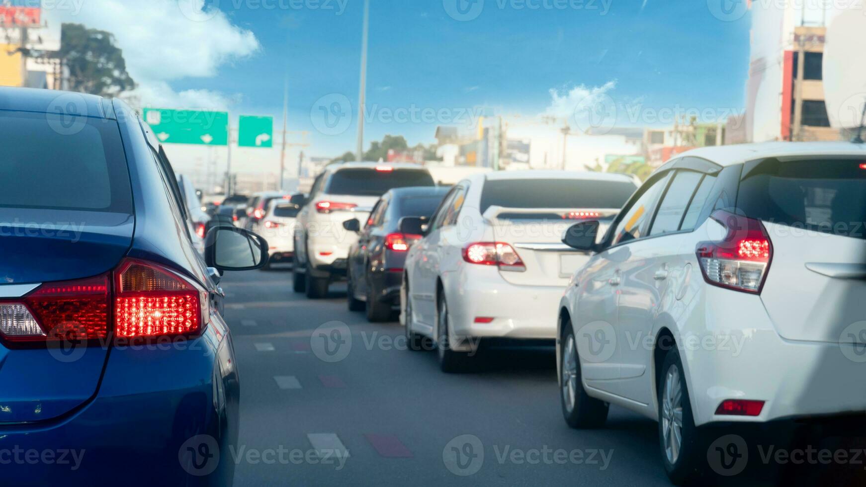 Transport of car on the asphalt road. Rear side of blue car with turn on brake light. Many cars parking in a long queue in the city. photo