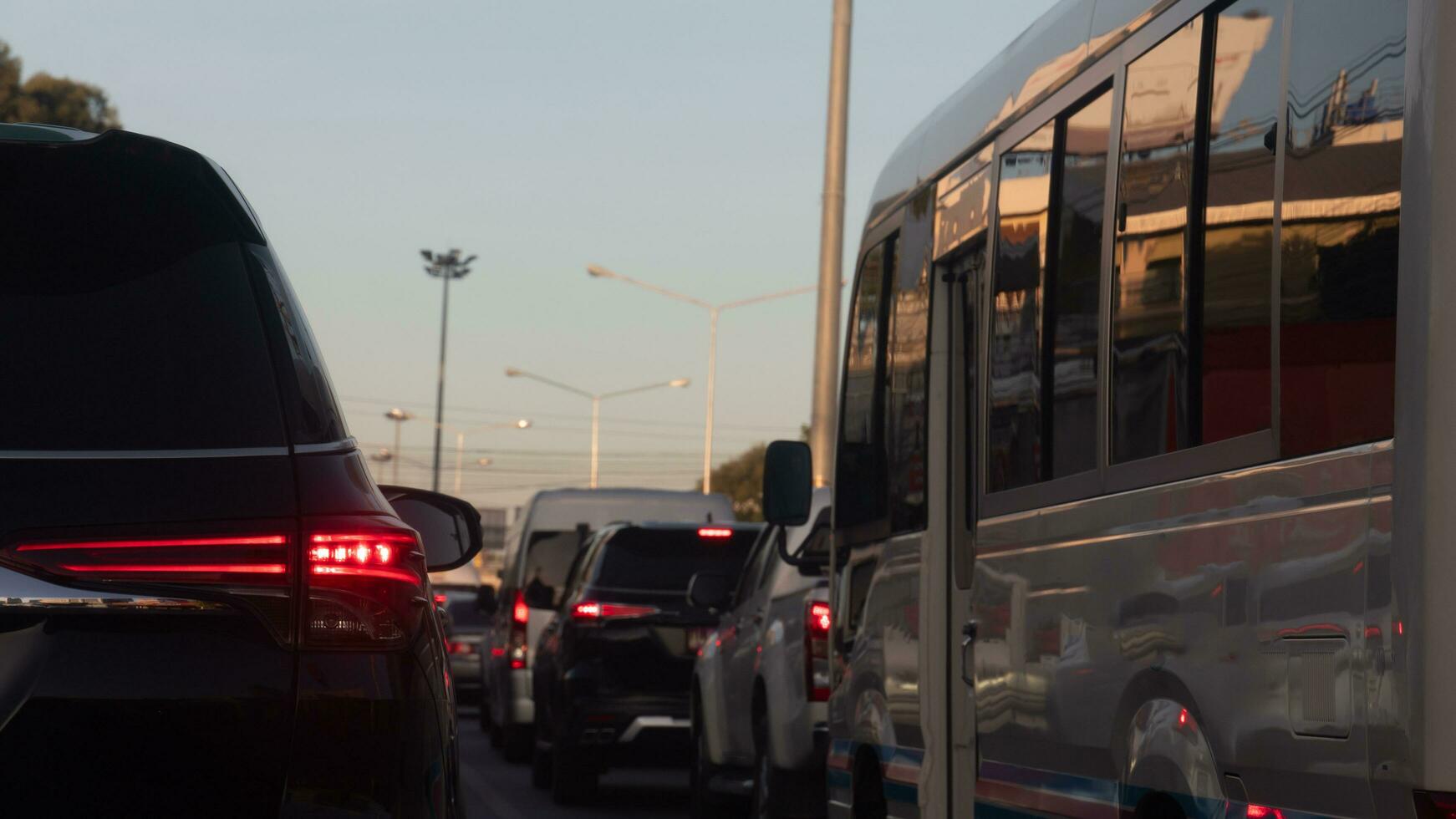 Rear side of black car with turn on brake light on the road. Traffic jam with many cars connected in a long queue. Environment of city in the morning. photo