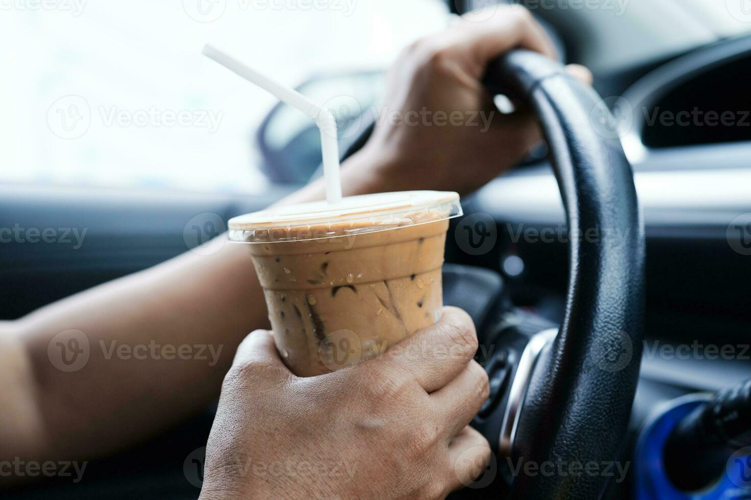 Asian woman driver hold ice coffee cup and sandwich bread for eat and drink in car, dangerous and risk an accident. photo