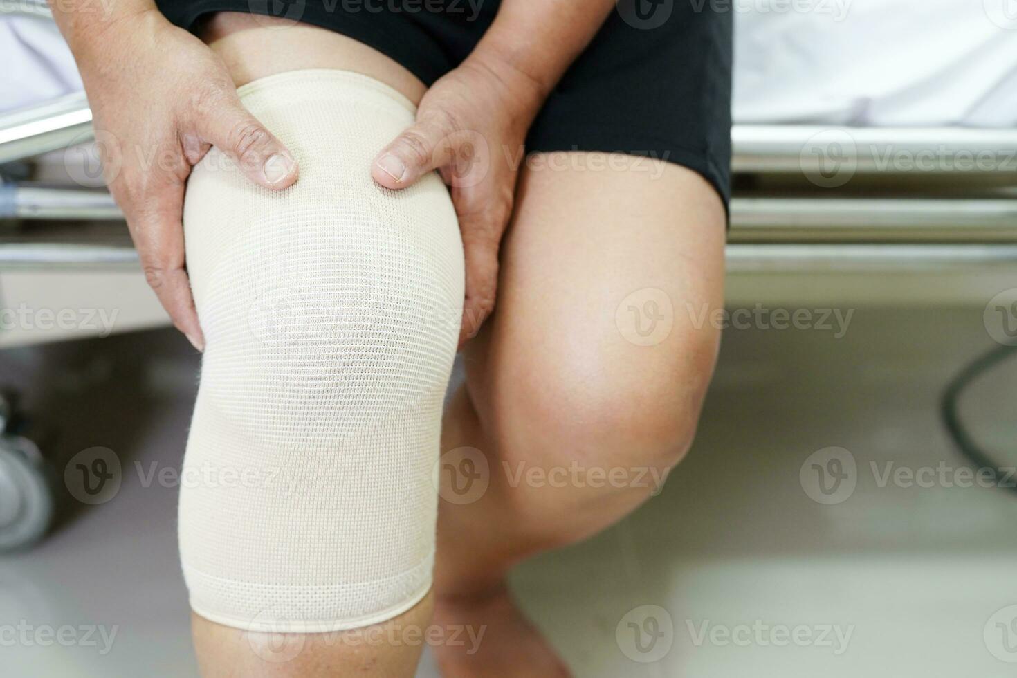 Asian senior woman wearing elastic support knee brace for reduce pain. photo