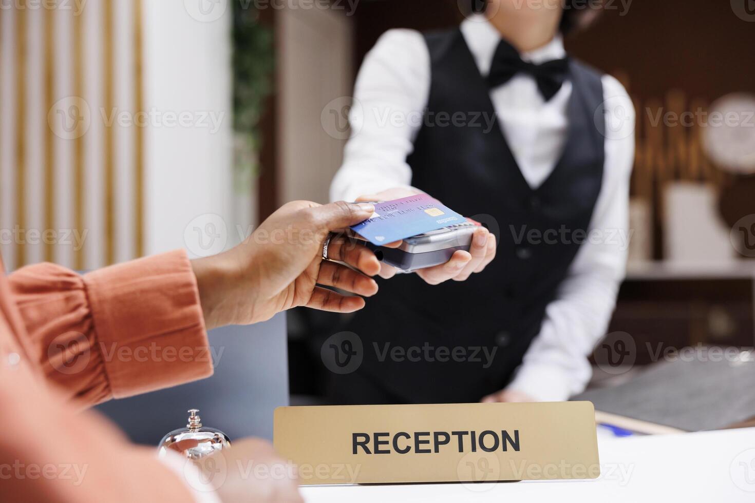 Female tourist paying at pos terminal in hotel lobby, using electronic payment at check in registration. Young resort guest using credit card at reception counter front desk. Close up. photo