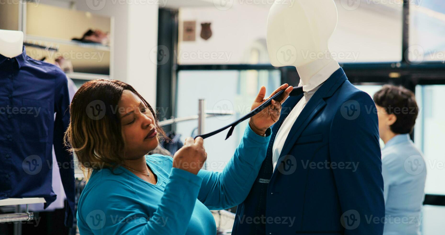 African american shopper analyzing at blue suit, checking merchandise material in clothing store. Shopaholic customer shopping for fashionable clothes, looking at new fashion collection photo