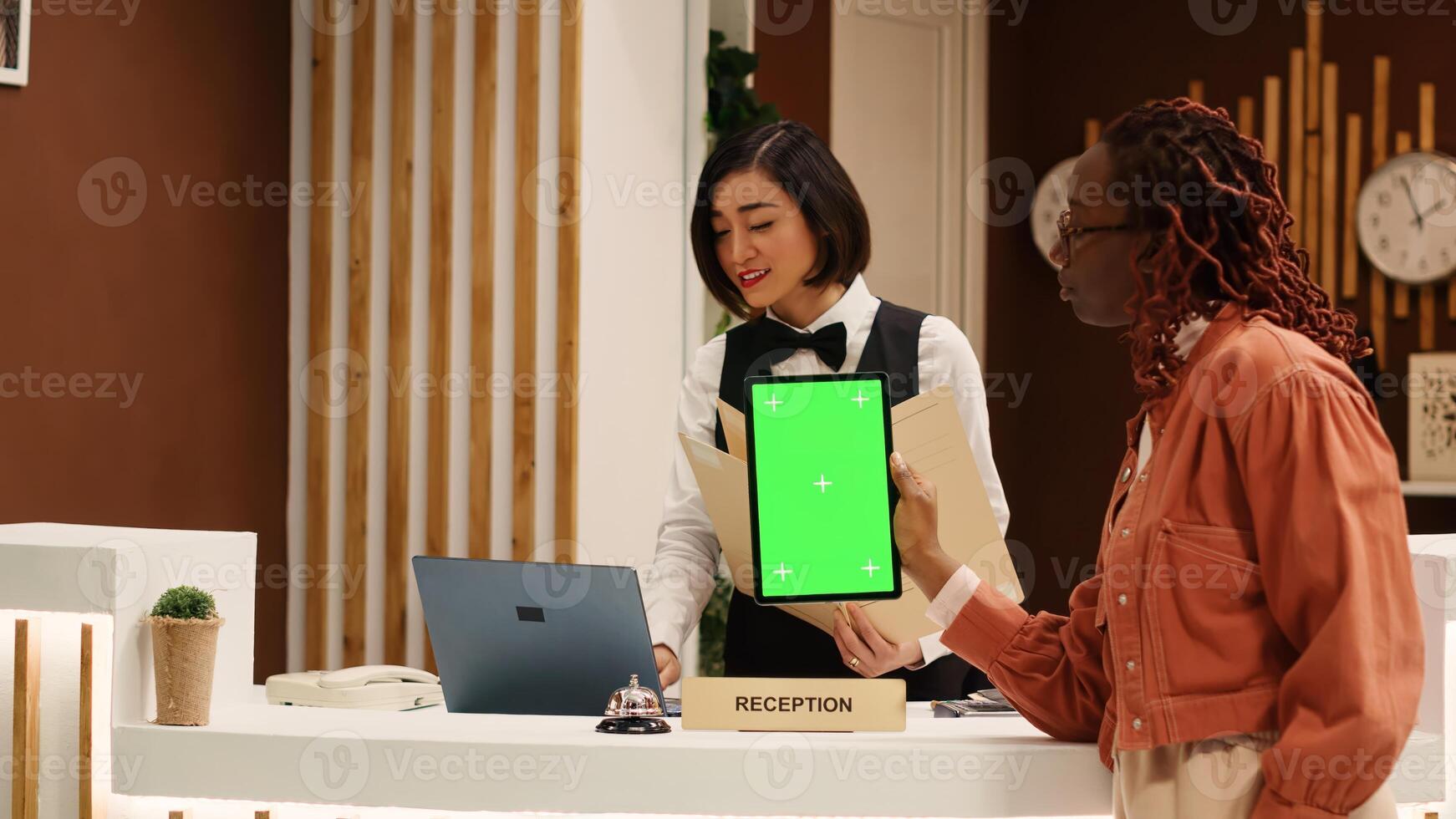 Weary tourist holding chroma key green screen mock up tablet at hotel reception desk after long flight, waiting for room payment to be processed. Guest in resort foyer doing check in photo
