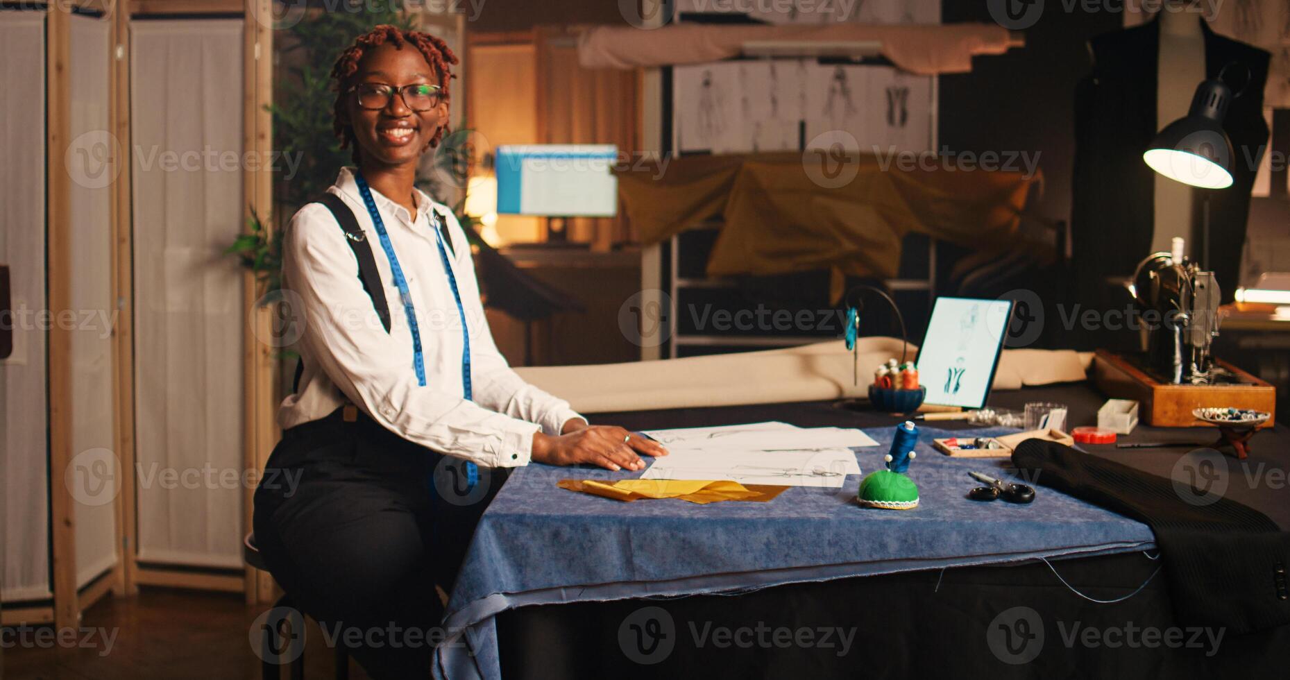 mujer diseñador comprobación ropa bocetos en lujo taller, mirando a moderno diseños a crear profesional Moda recopilación. joven Sastre trabajando en hecho a mano ropa línea, costura. foto