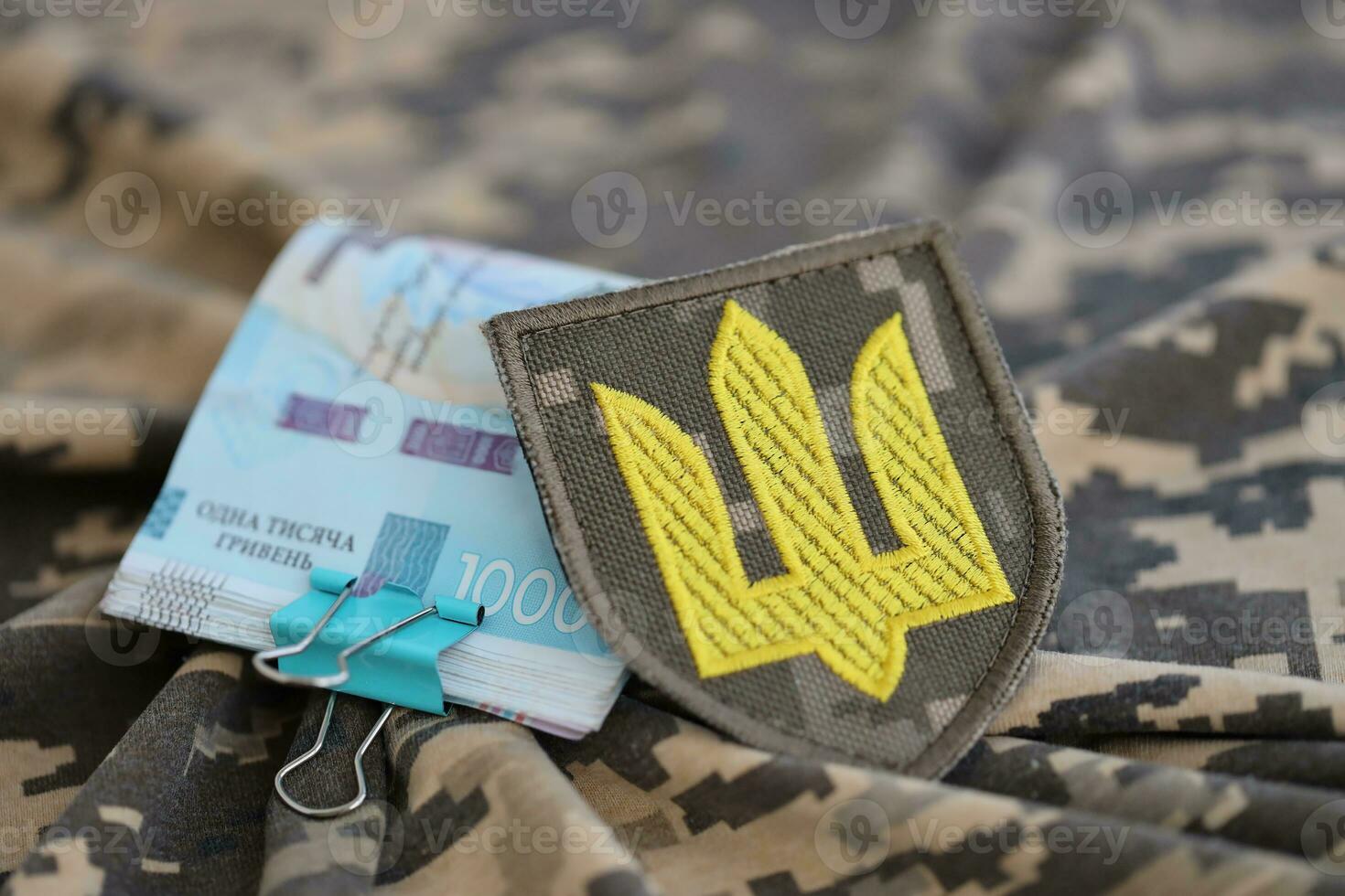 Ukrainian army symbol and bunch of hryvnia bills on military uniform. Payments to soldiers of the Ukrainian army, salaries to the military photo