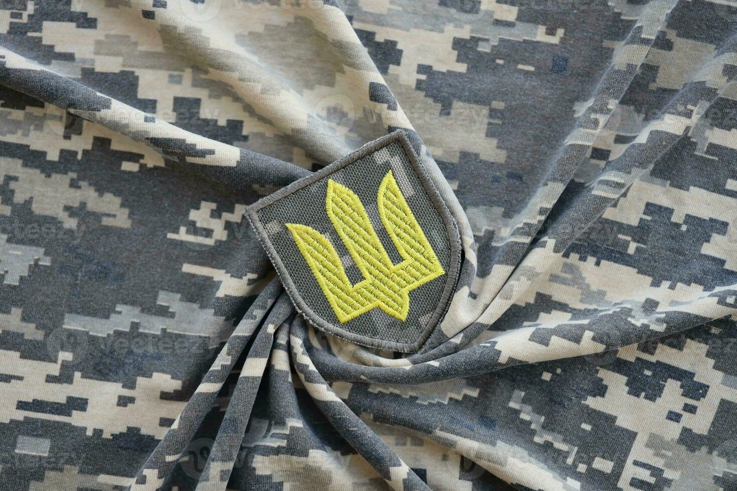 Symbol of Ukrainian army on the camouflage uniform of a Ukrainian soldier. The concept of war in Ukraine, patriotism and protecting your country from occupiers photo