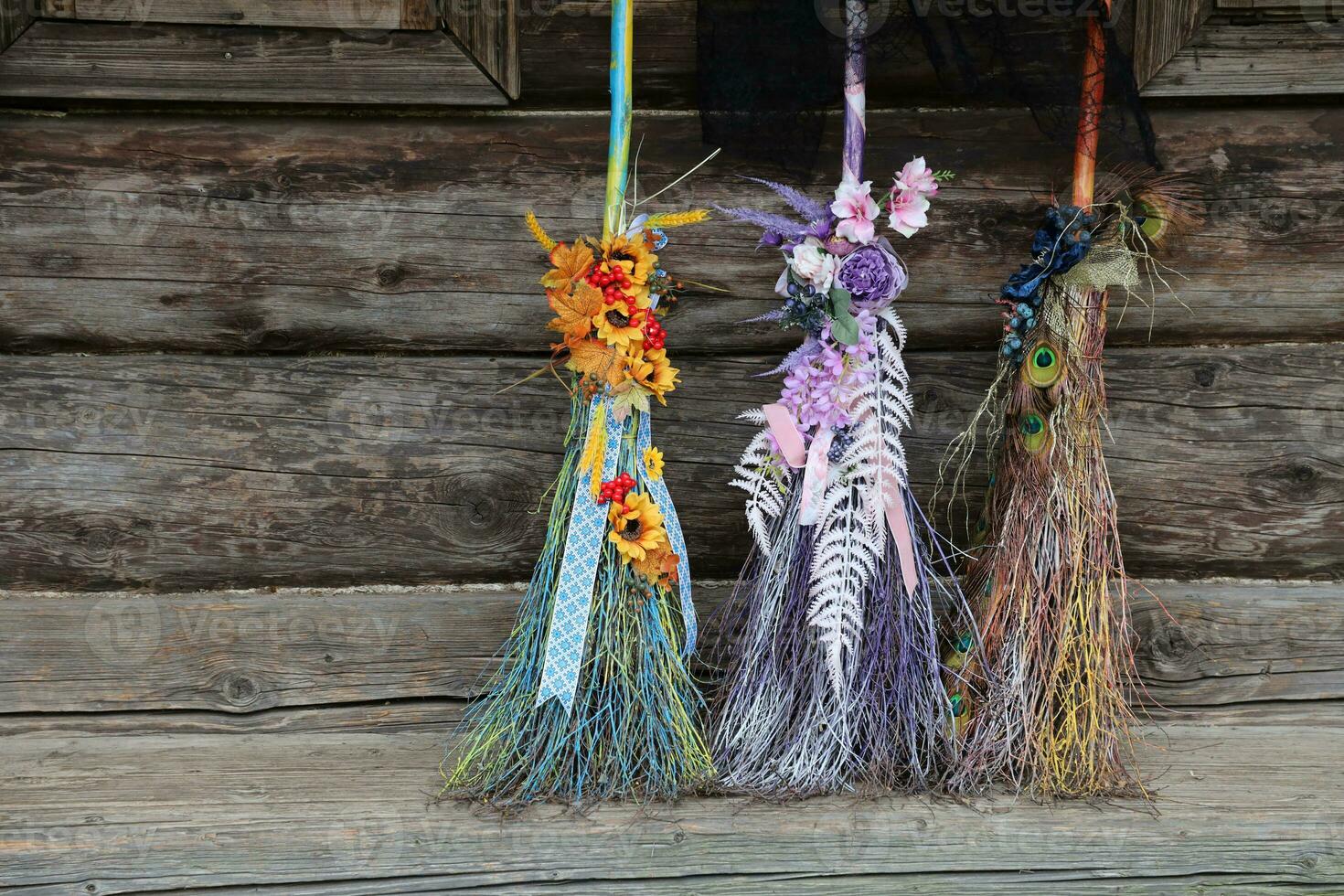 Three different brooms of witches stand at the old wooden hut house photo