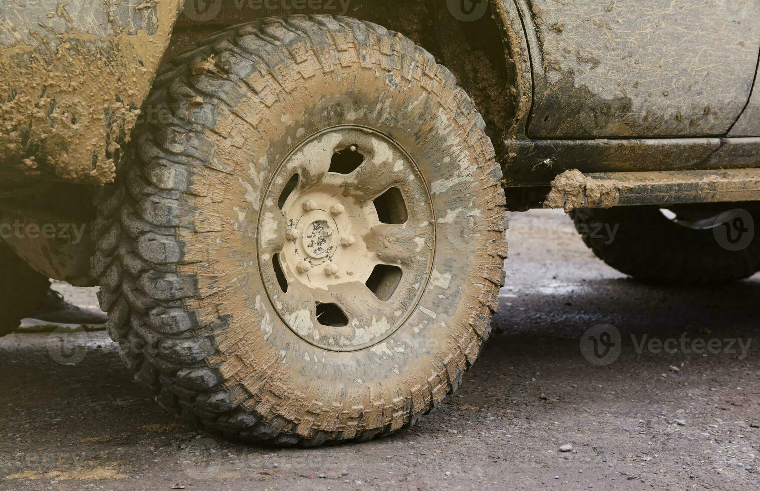 Wheel closeup in a countryside landscape with a mud road. Off-road 4x4 suv automobile with ditry body after drive in muddy road photo