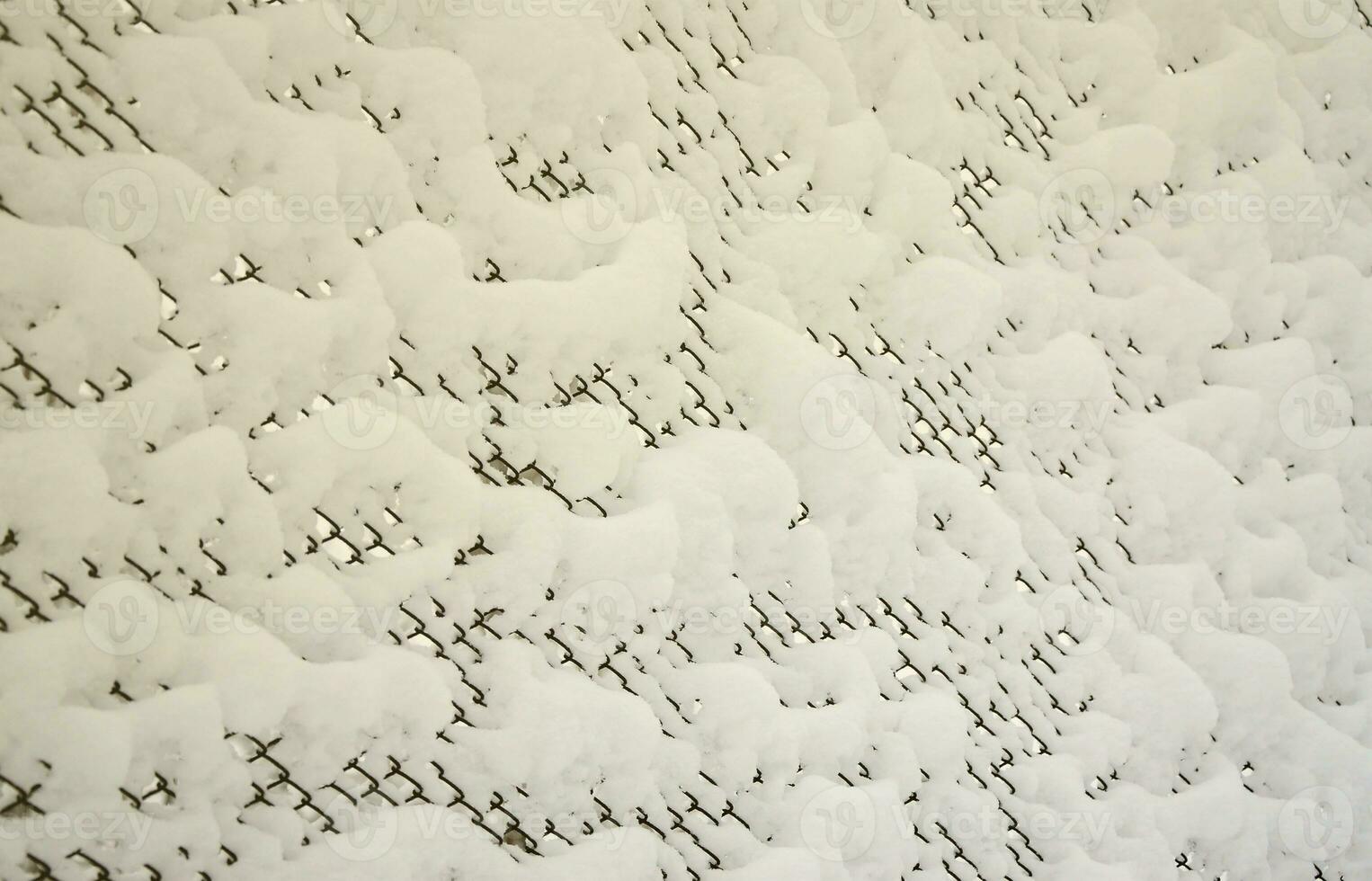 Close-up metal mesh covered with a thick layer of snow in the cells photo