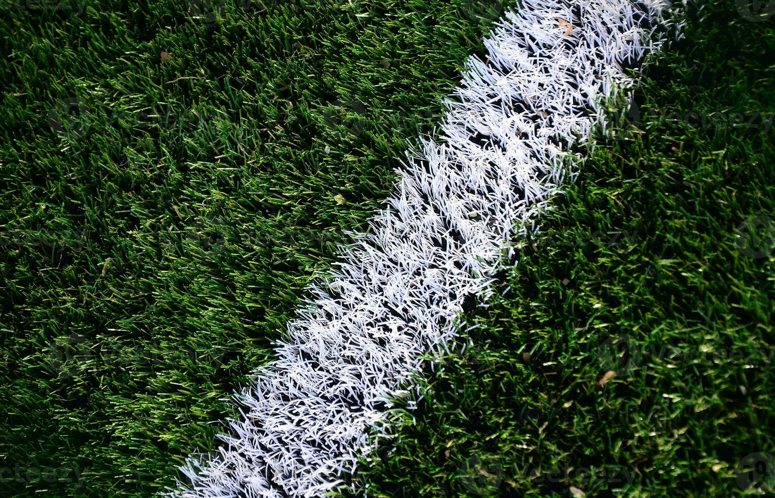 White stripe on a bright green artificial grass soccer field photo
