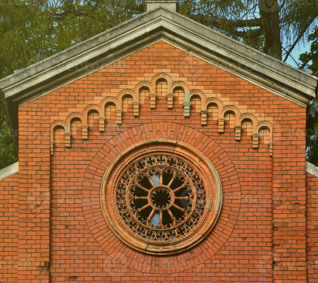 Texture front part of an ancient brick crypt with a round patterned carved window in the cemetery photo