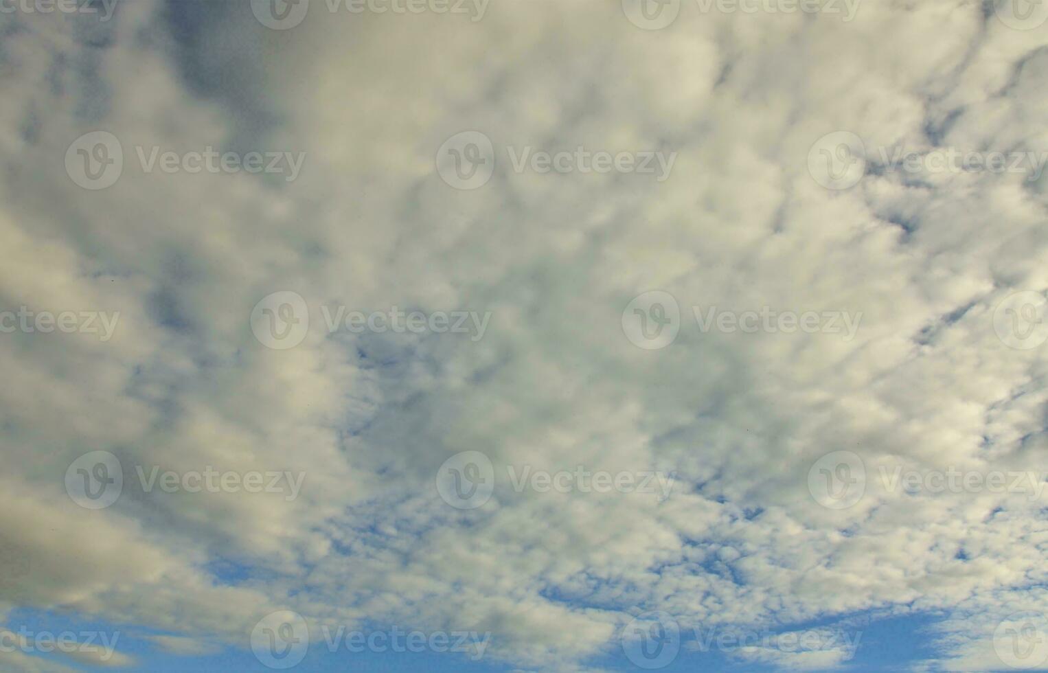 A blue cloudy sky with many small clouds blocking the sun photo