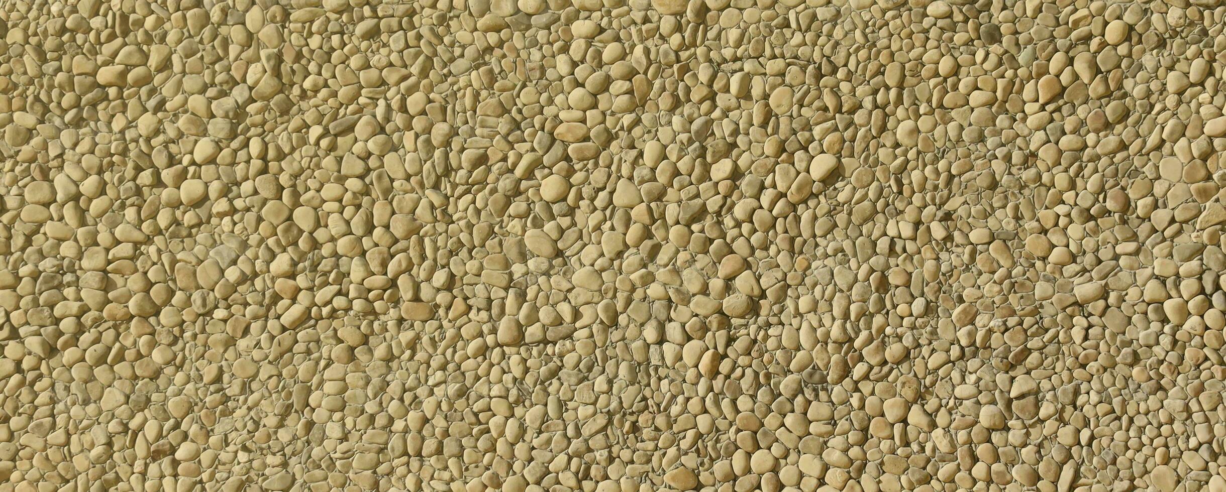 Texture of a stone wall with small round pebble stones. Part of a stone wall as a background or texture photo