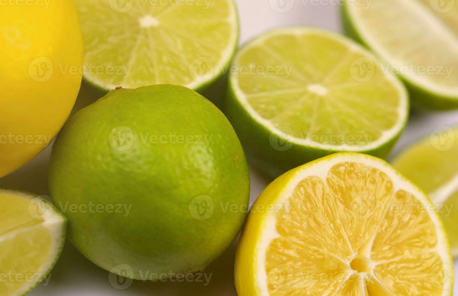 Many halves and slices of yellow lemon and green lime on light white table. Fresh fruits on kitchen wooden top photo