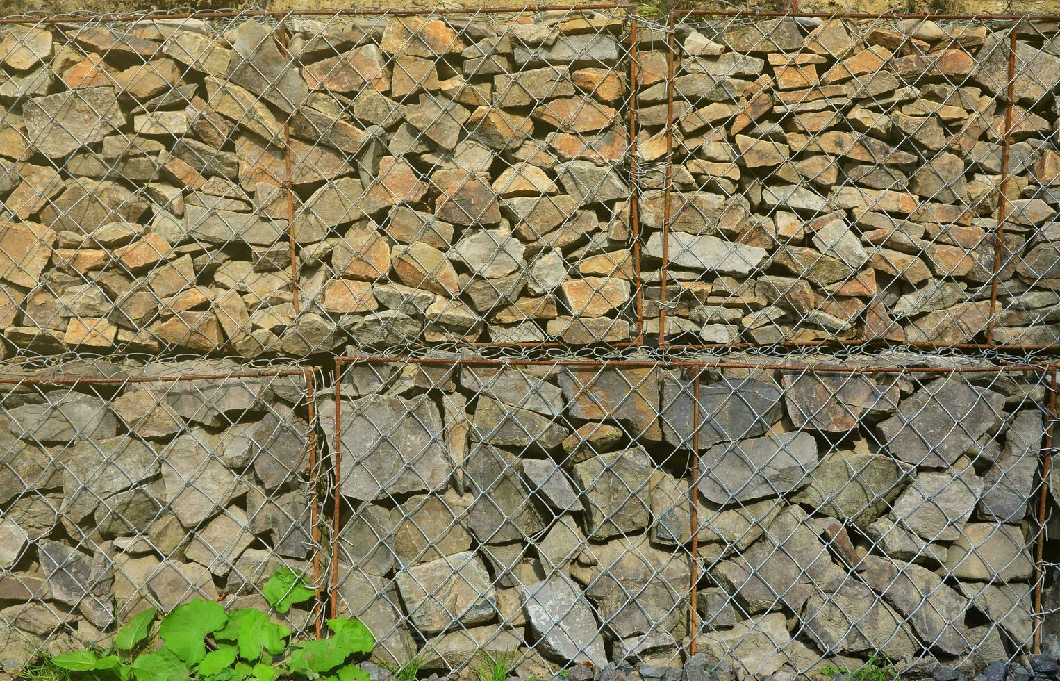 Photo of several gabions. The mesh cells of the cubic form are filled with mountain stones of various shapes that let water through the rain, but protect the road from falling stones