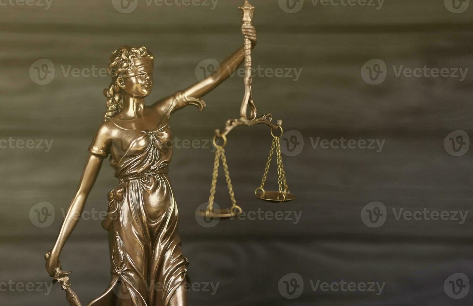 The Statue of Justice - lady justice or justitia the Roman goddess of Justice. Statue on black wooden wall. Concept of judicial trial, courtroom process and lawyers work photo