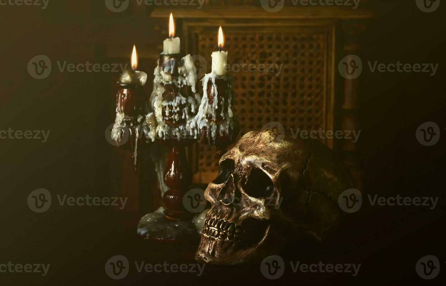 Old battered skull lies with an antique wooden candlestick photo