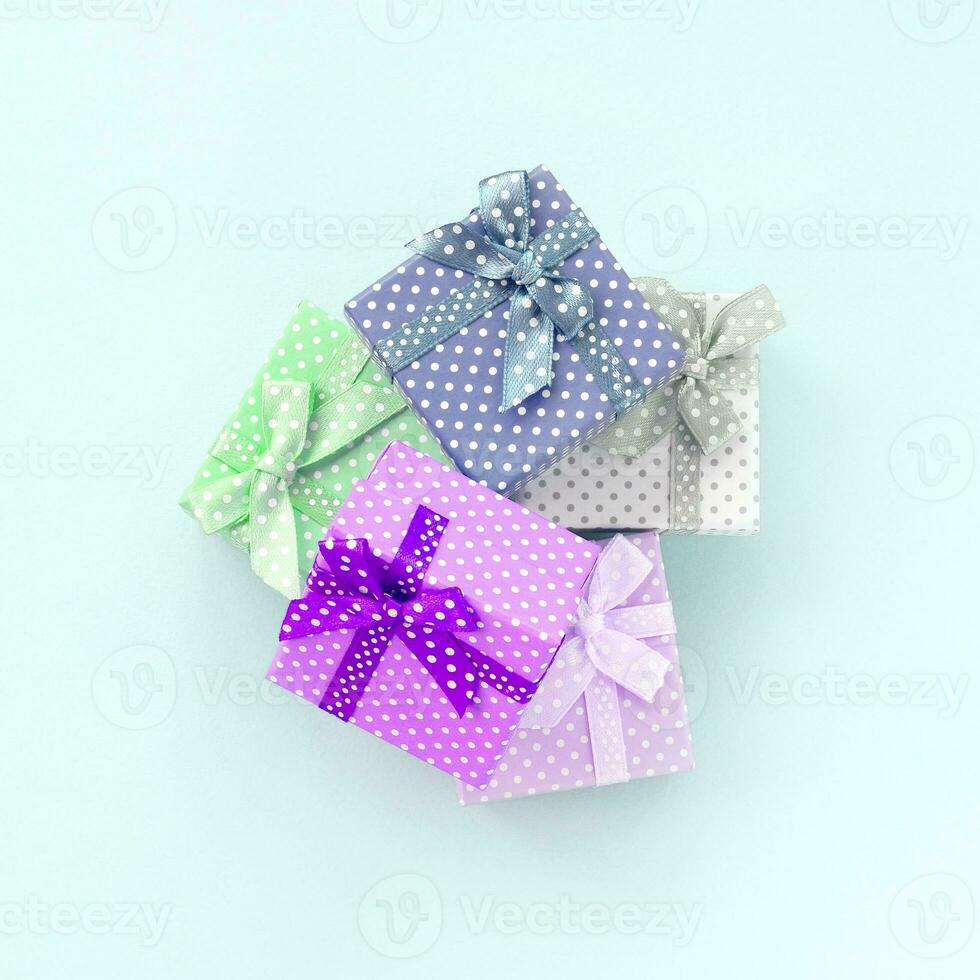 Pile of a small colored gift boxes with ribbons lies on a violet background. Minimalism flat lay top view photo