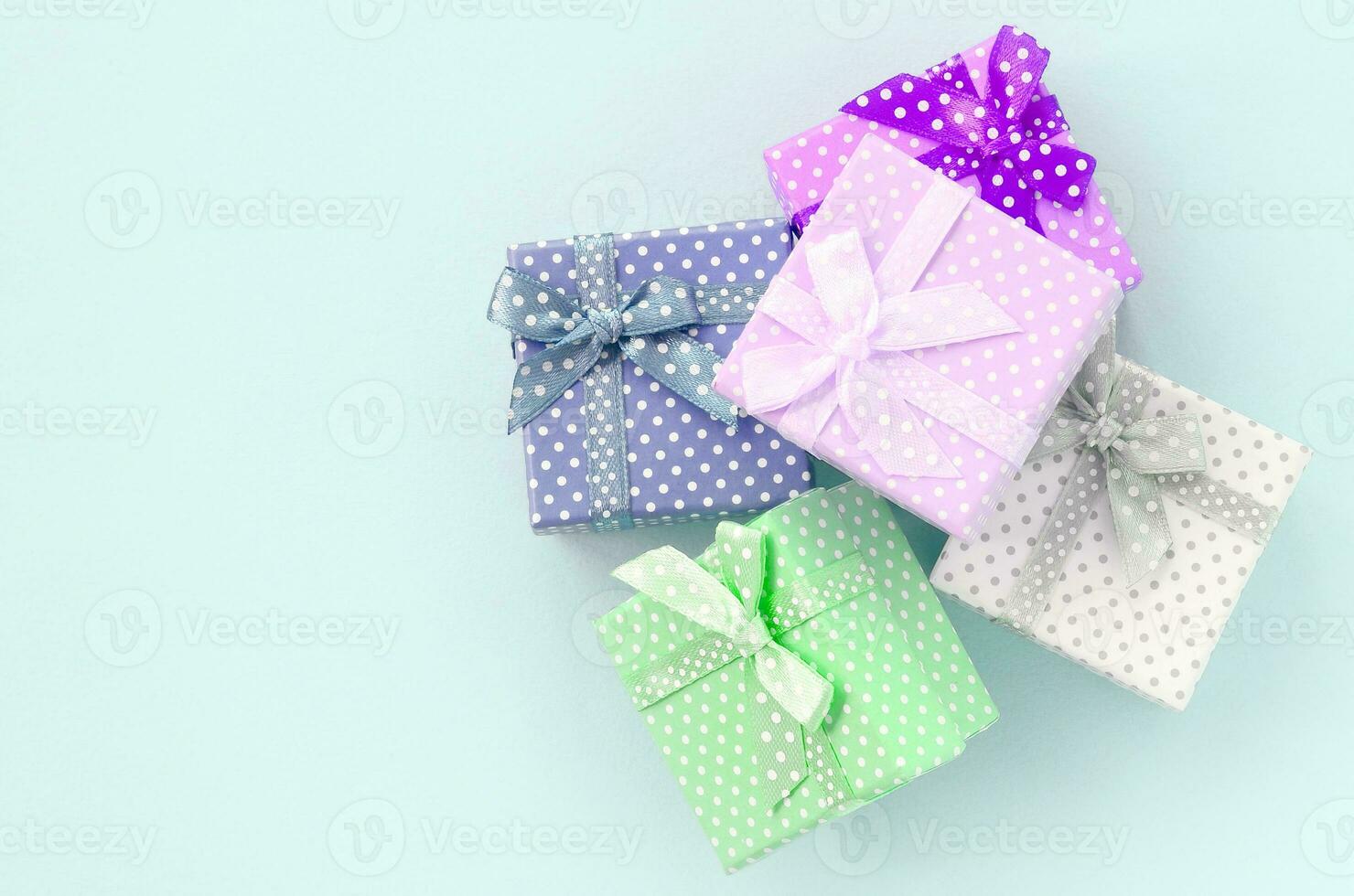 Pile of a small colored gift boxes with ribbons lies on a violet background. Minimalism flat lay top view photo