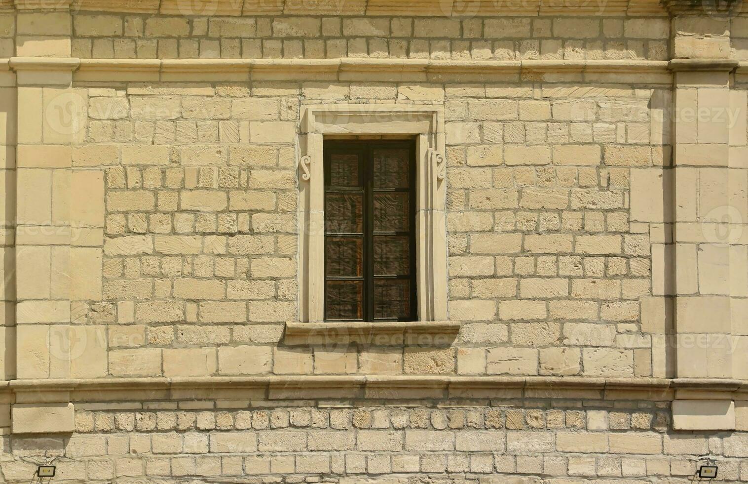 Very old window in brick stone wall of castle or fortress of 18th century. Full frame wall with window photo