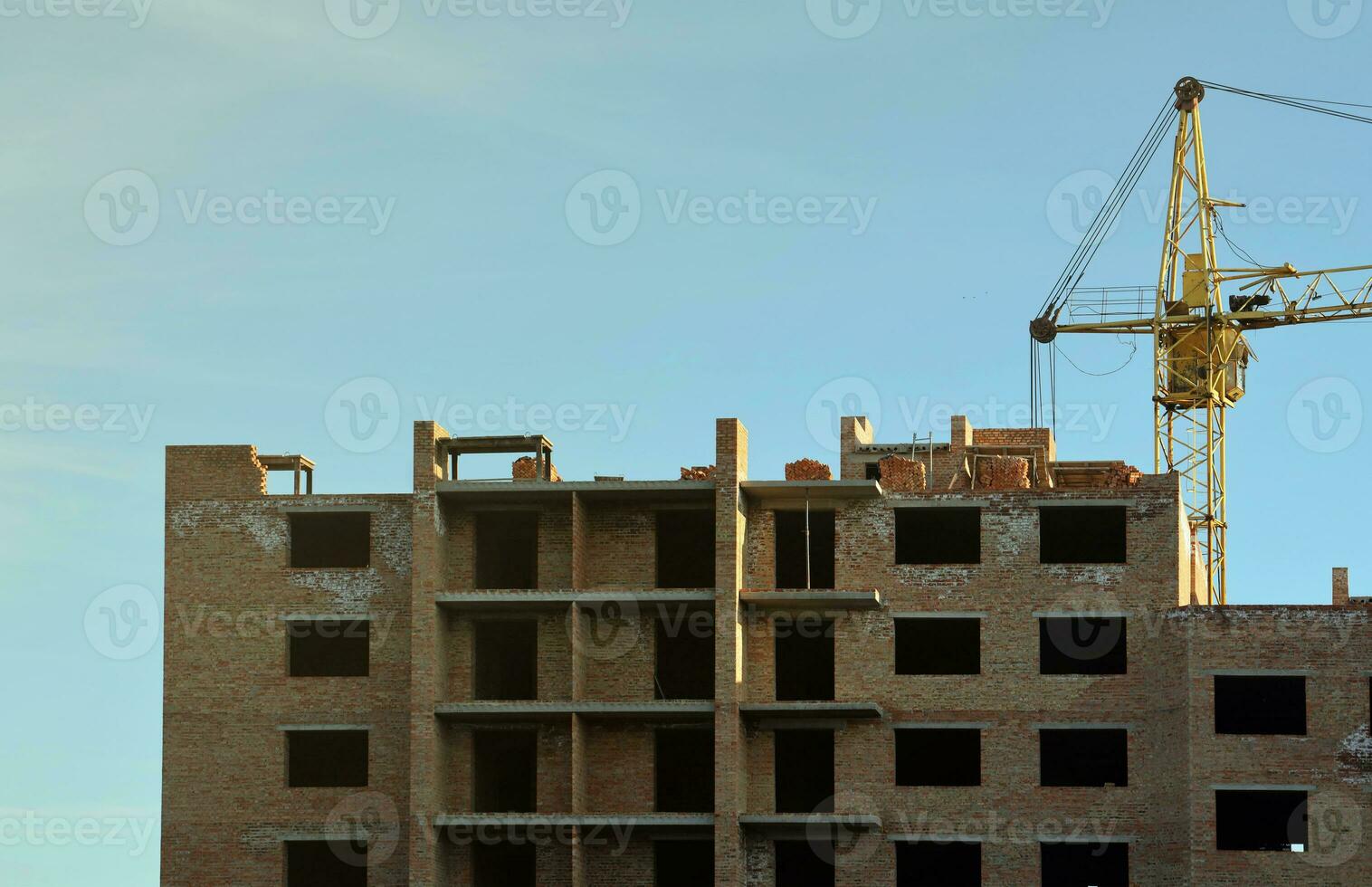 View of a large construction site with buildings under construction and multi-storey residential homes. Tower cranes in action on blue sky background. Housing renovation concept photo