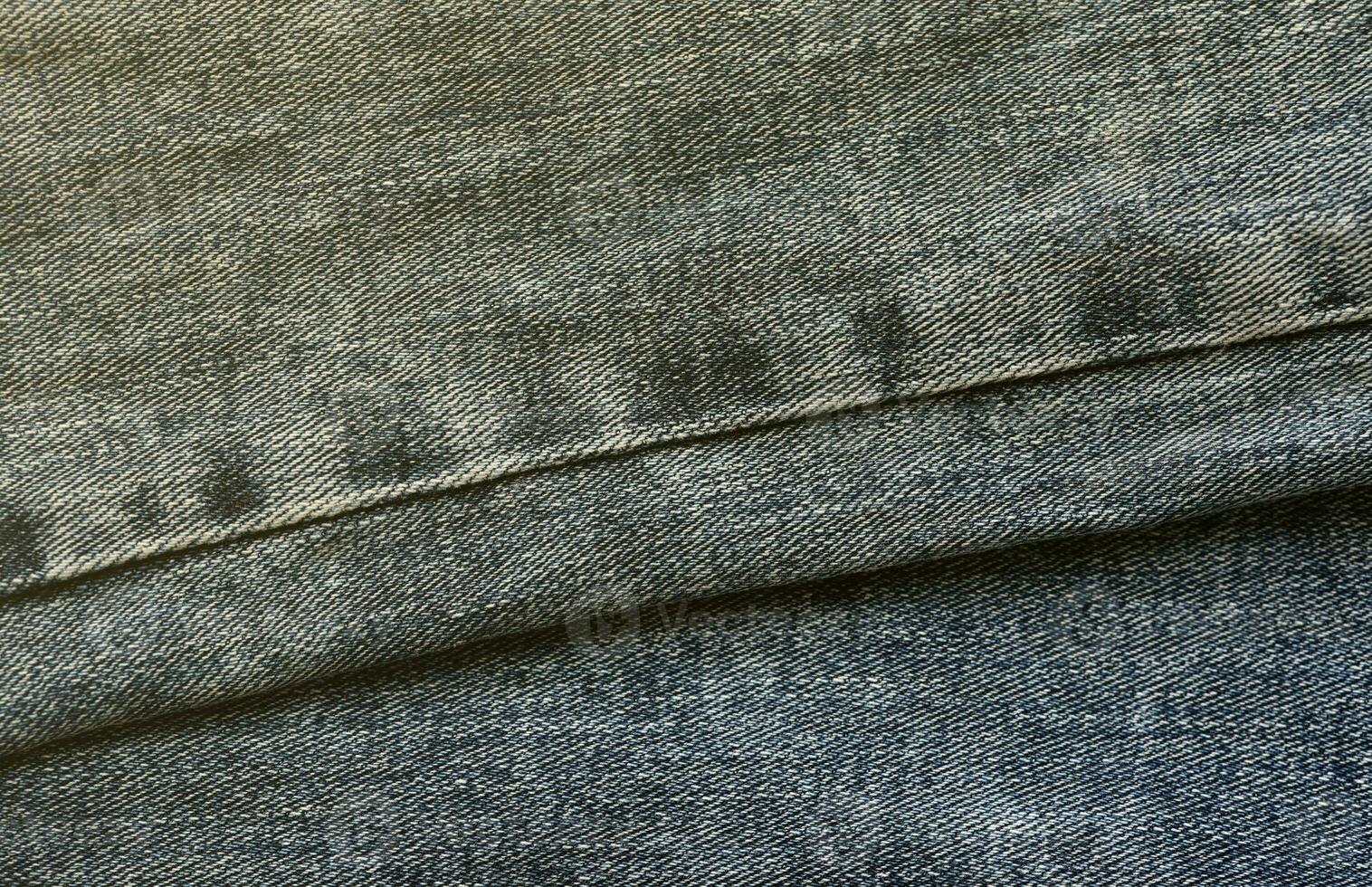 Detailed abstract texture of dark blue denim cloth. Background image of old used denim trousers fabric photo