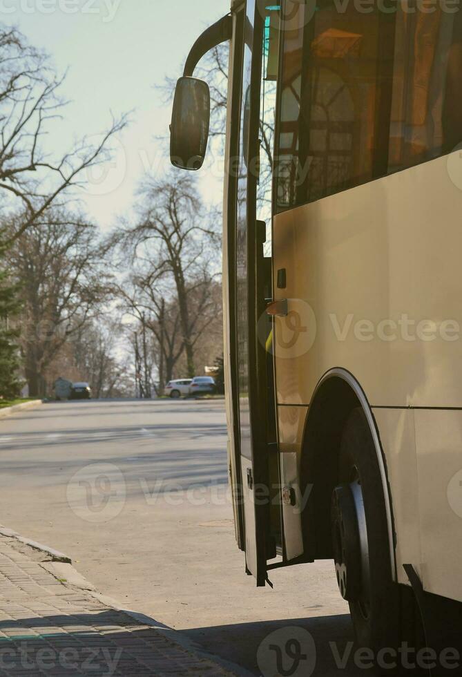 Photo of the hull of a large and long yellow bus. Close-up front view of a passenger vehicle for transportation and tourism