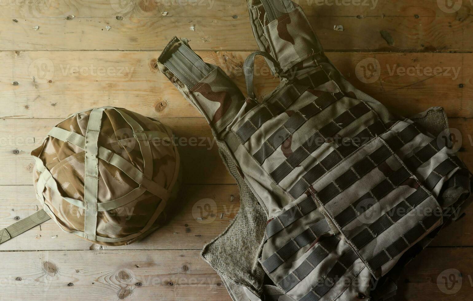 A military helmet of a Ukrainian soldier with a heavy bulletproof vest on wooden table in checkpoint dugout photo