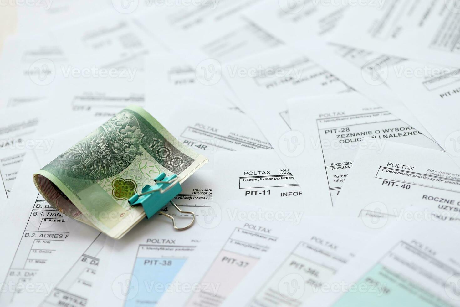 Polish zloty money PLN on big amount of polish PIT, CIT and VAT tax forms close up. Accounting, bureaucracy and taxpayers routine photo