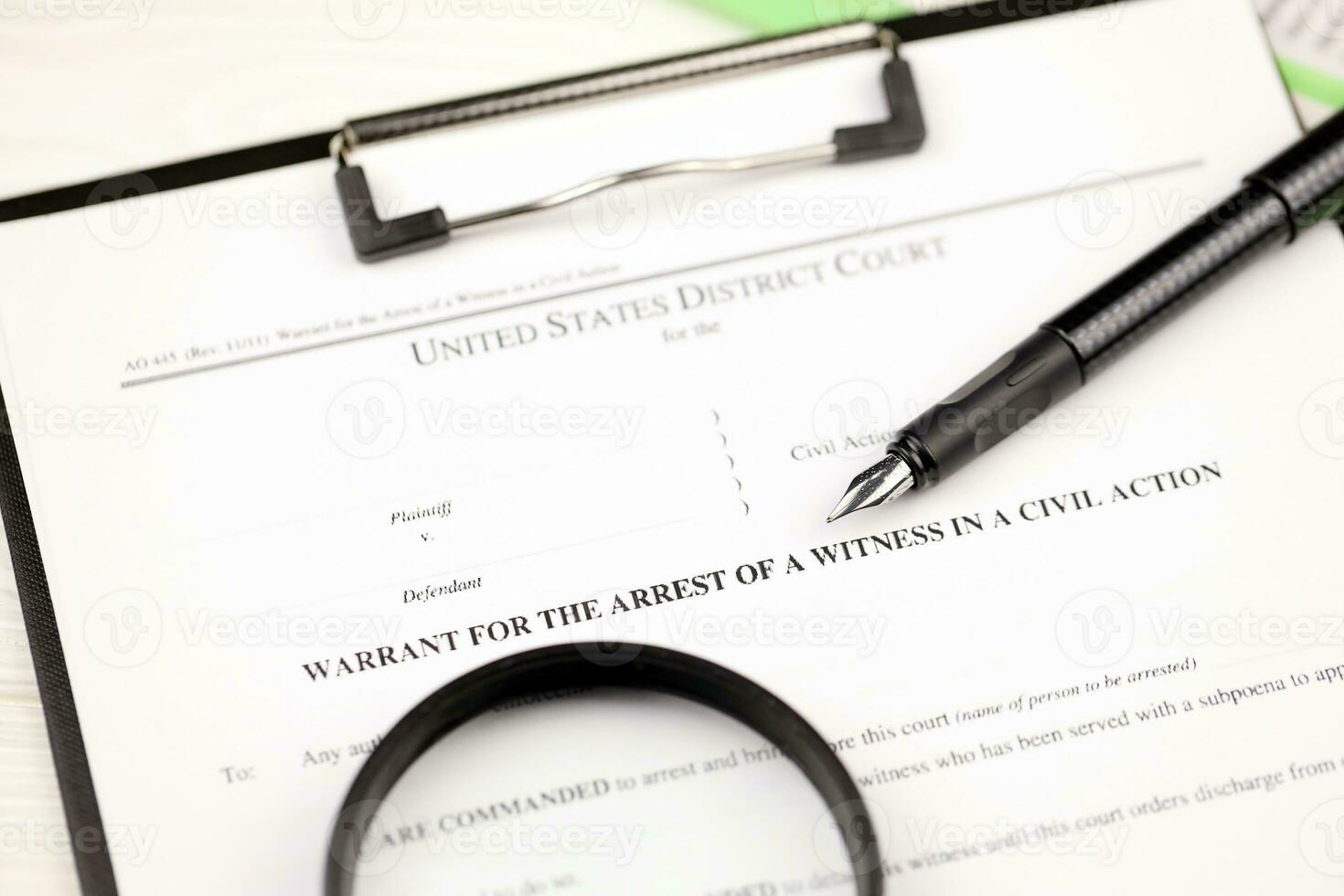 District court warrant for the arrest of a witness in a civil action papers on A4 tablet lies on office table with pen and magnifying glass photo