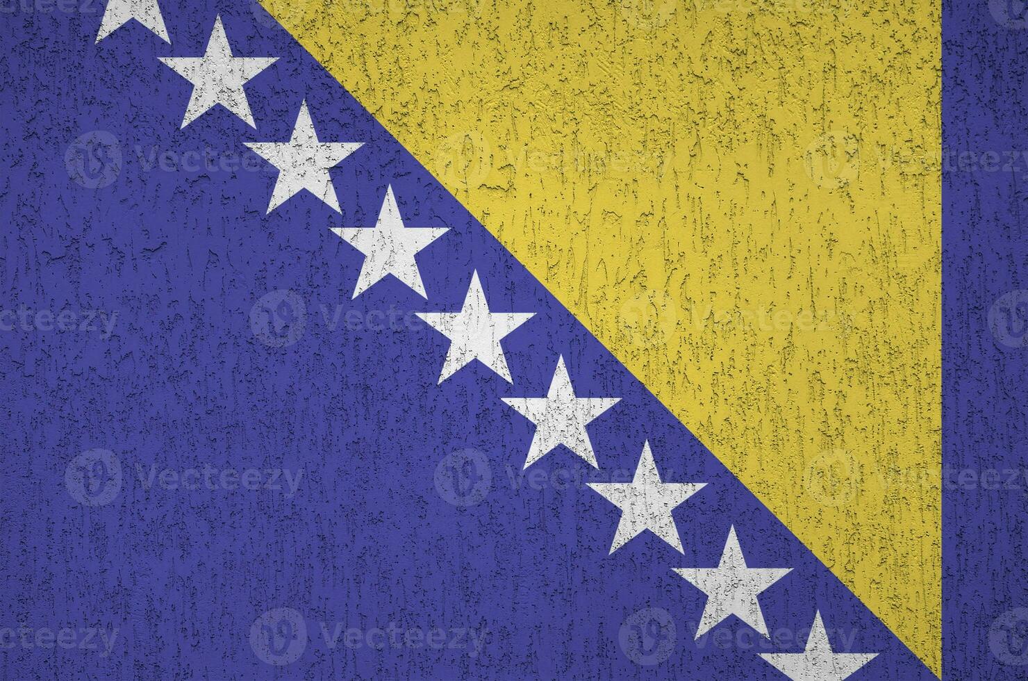 Bosnia and Herzegovina flag depicted in bright paint colors on old relief plastering wall. Textured banner on rough background photo