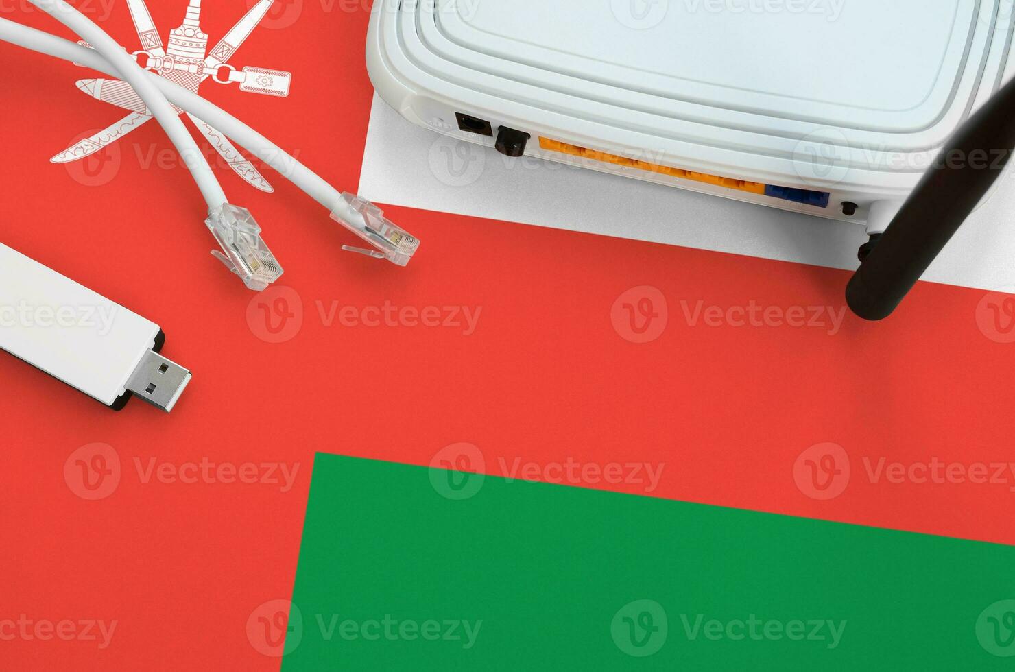 Oman flag depicted on table with internet rj45 cable, wireless usb wifi adapter and router. Internet connection concept photo