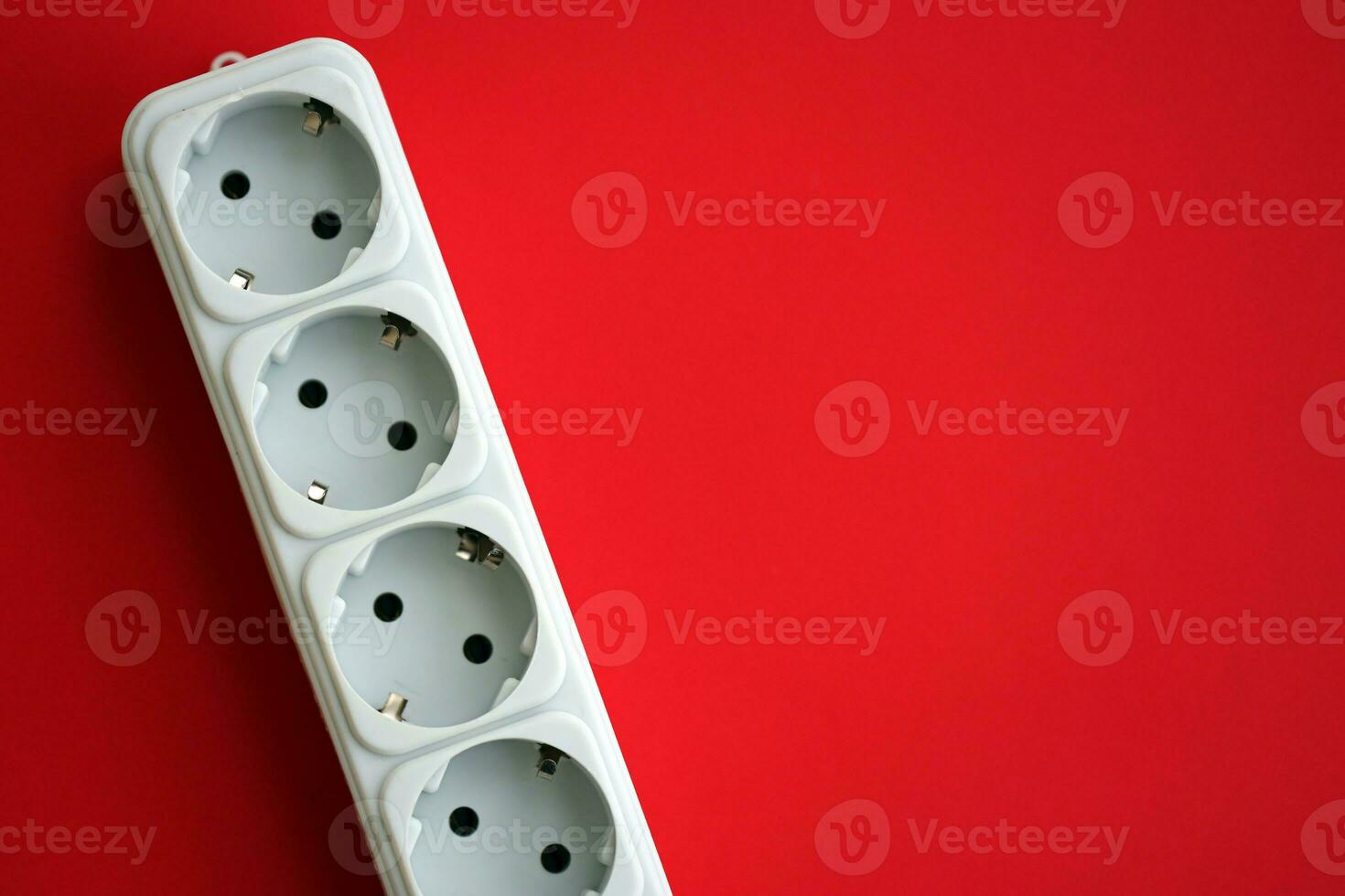 White electrical multi plug extender with european socket on bright red background photo