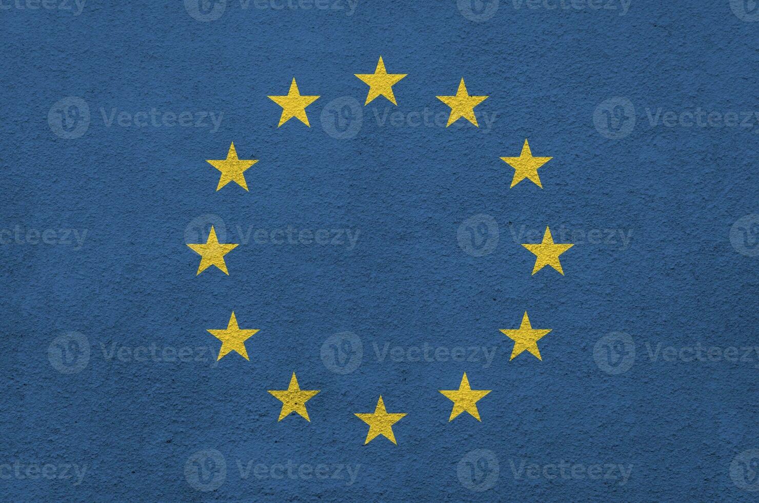 European union flag depicted in bright paint colors on old relief plastering wall. Textured banner on rough background photo