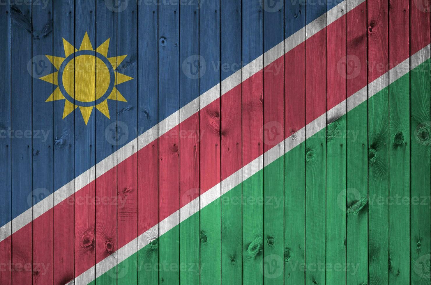 Namibia flag depicted in bright paint colors on old wooden wall. Textured banner on rough background photo