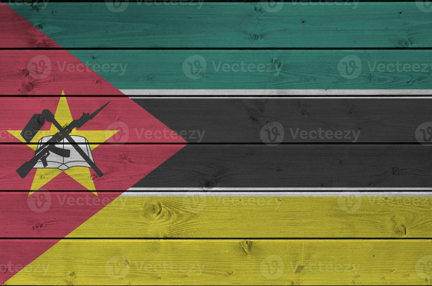 Mozambique flag depicted in bright paint colors on old wooden wall. Textured banner on rough background photo