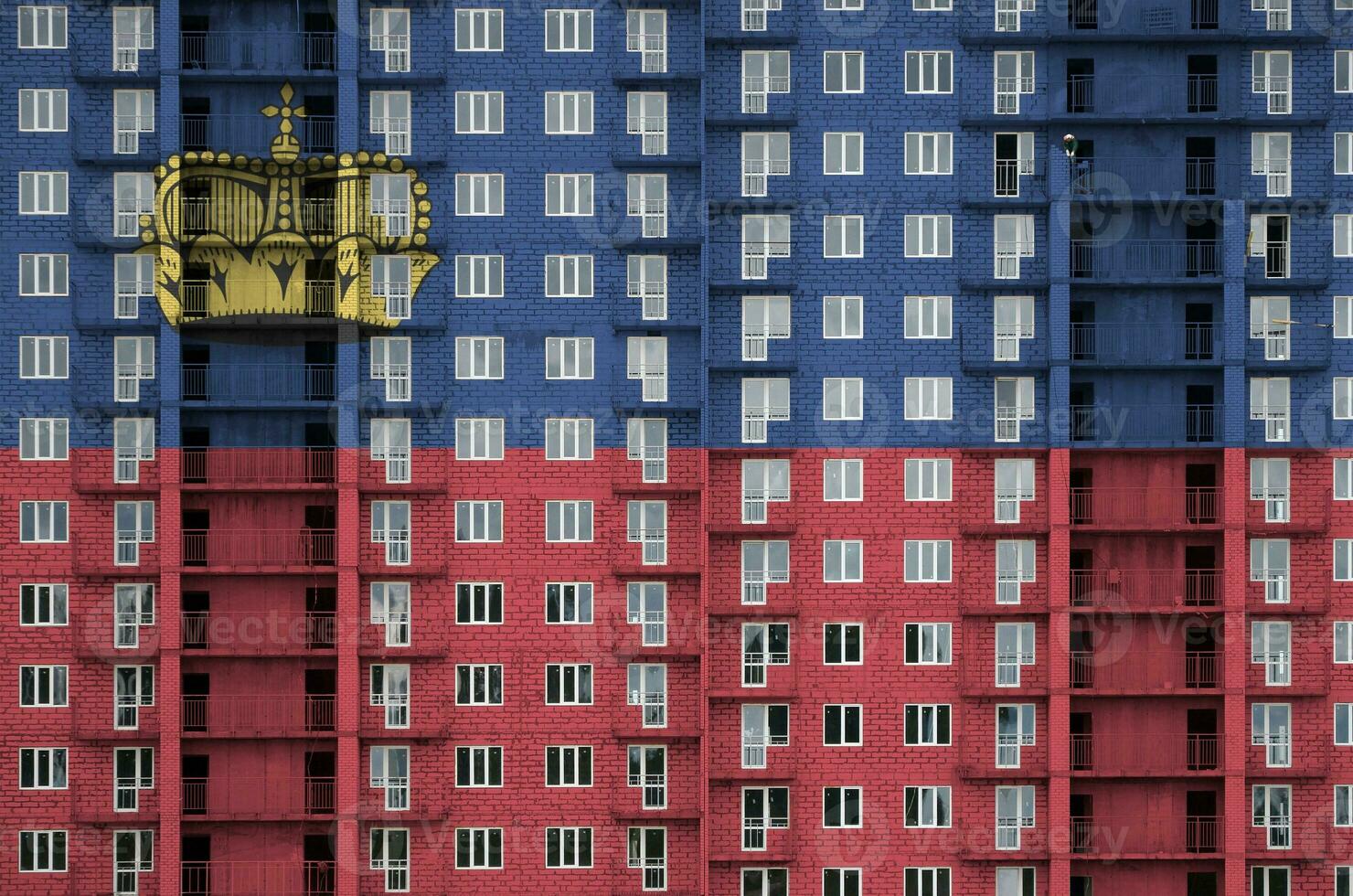 Liechtenstein flag depicted in paint colors on multi-storey residental building under construction. Textured banner on brick wall background photo