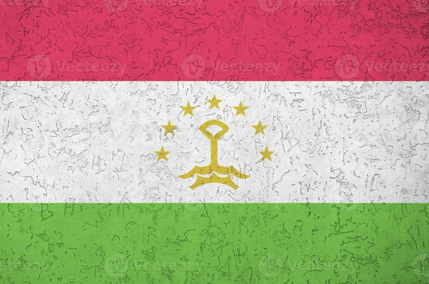 Tajikistan flag depicted in bright paint colors on old relief plastering wall. Textured banner on rough background photo