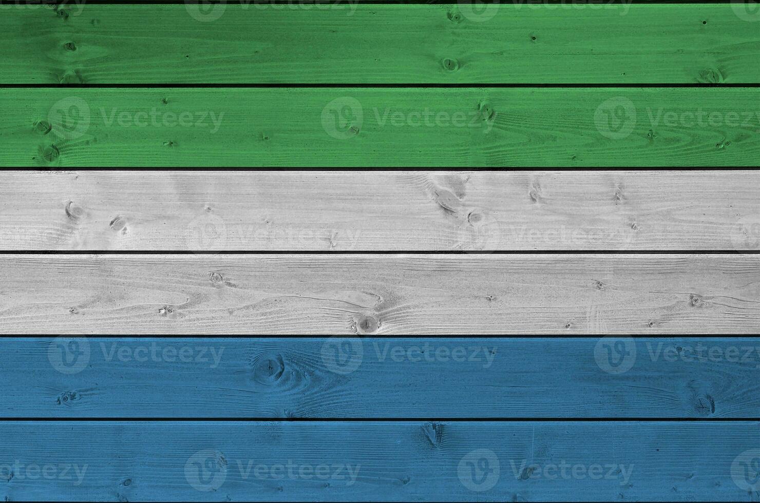 Sierra Leone flag depicted in bright paint colors on old wooden wall. Textured banner on rough background photo