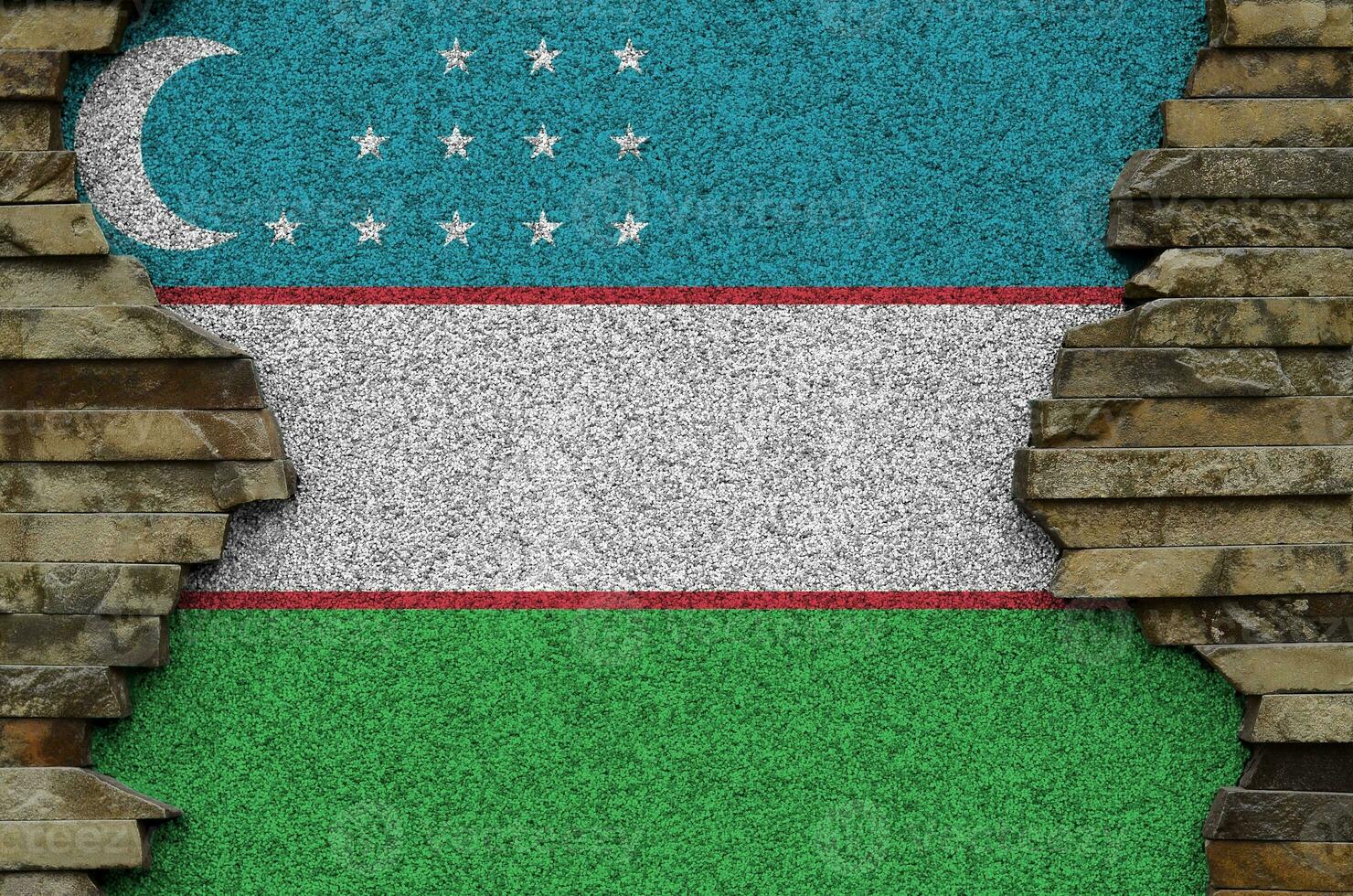 Uzbekistan flag depicted in paint colors on old stone wall closeup. Textured banner on rock wall background photo
