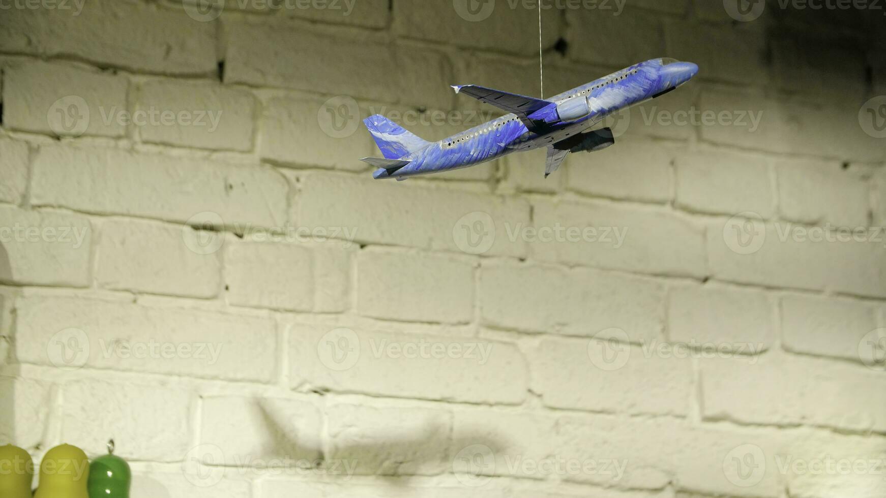 Homemade airplane in the room. On the background of stone wall hanging toy airplane on a rope, the concept of hand made photo